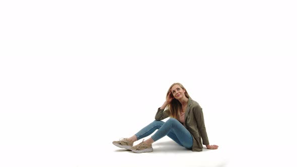 Pleasing Caucasian Blonde Girl Wearing Sneakers Denim and Jacket Smiling Sitting on the Floor and alt