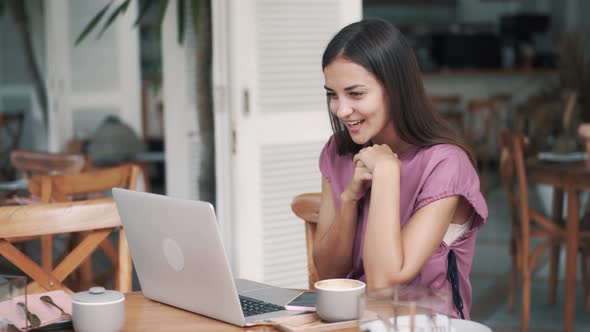 Nice Woman Sitting in Cafe with Laptop Has Video Calling By Webcam alt