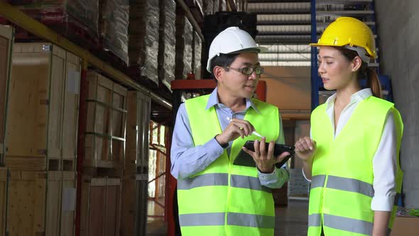 Asian supervisor talking about work with female worker at factory warehouse