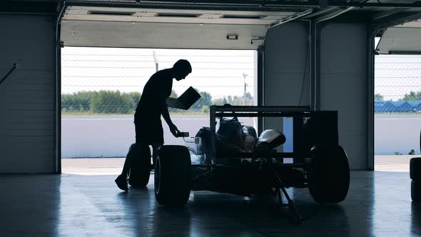 A Mechanic with a Laptop is Checking a Racing Car alt