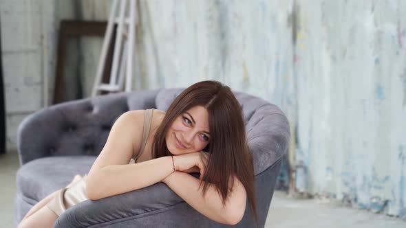 A Woman Lies on the Couch and Poses for a Photo Shoot in a Photo Studio Loft alt