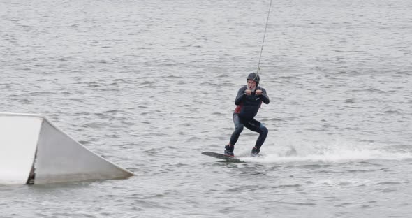 Wakeboarding in a Lake Near the Forest, Adult Man Surfs on the Water, Ride on a Wakeboarding Board alt
