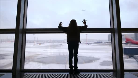 Little Girl in Airport Near Big Window While Wait for Boarding