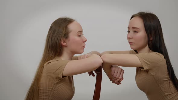 Concentrated Young Twin Sisters Looking at Each Other Turning to Camera and Back alt