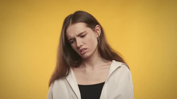 Young Adult Caucasian Woman is Unhappy on a Bright Yellow Background alt