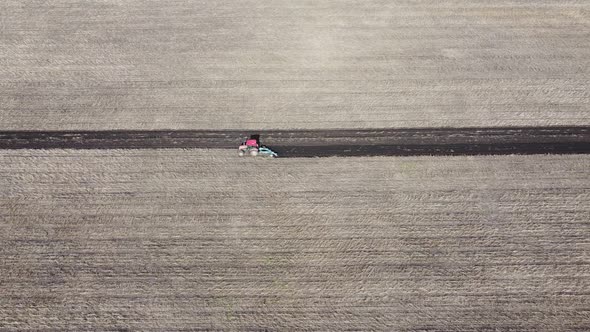 Shooting From Drone Flying Over Tractor with Harrow System Plowing Ground on Cultivated Farm Field