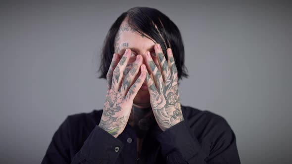 Closeup Tattooed Male Hands Opening Face and Neck of Young Man with Tattoos alt