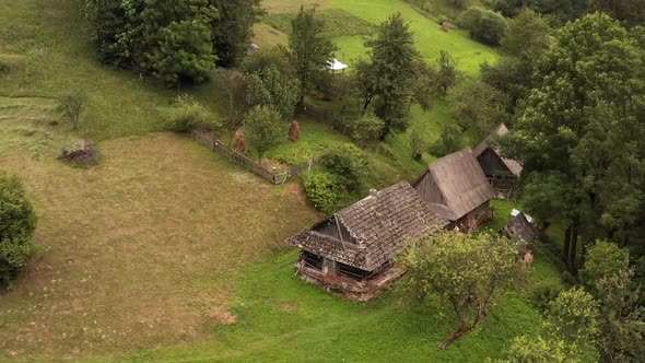 Aerial drone view of old wooden house among green trees on a mountain slope
