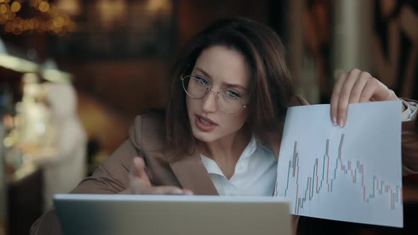Angry Business Woman Sitting at Cafe Table and Having Serious Conversation Via Video Call alt