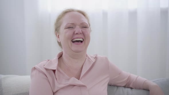 Close-up of Caucasian Adult Woman Laughing. Portrait of Cheerful Lady Having Fun Alone Indoors alt