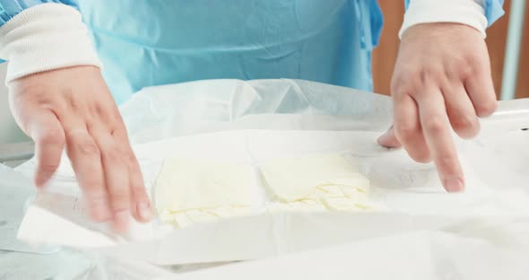 Closeup Male Veterinarian Hands While He Unpacks Surgical Gloves and Wears Them in Operational Room alt