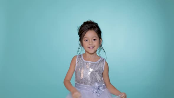 Beautiful Little Child Girl in Silver Dress Dancing on Blue Background