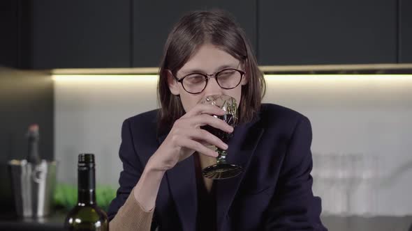 Portrait of Depressed Brunette Man in Eyeglasses Drinking Wine From Glass and Falling on the Table alt