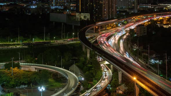 Highway interchange junction and traffic in Bangkok outskirt, at night; panning right - time lapse