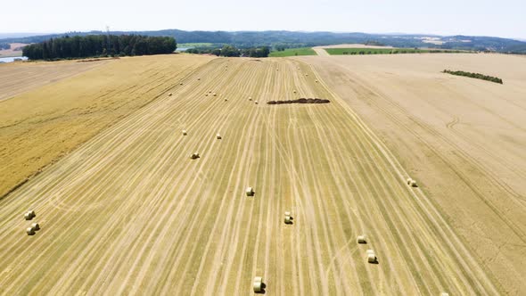 Aerial Drone Shot  Brown Field with Hay Bales in a Rural Area on a Sunny Day  Drone Flies Backward alt
