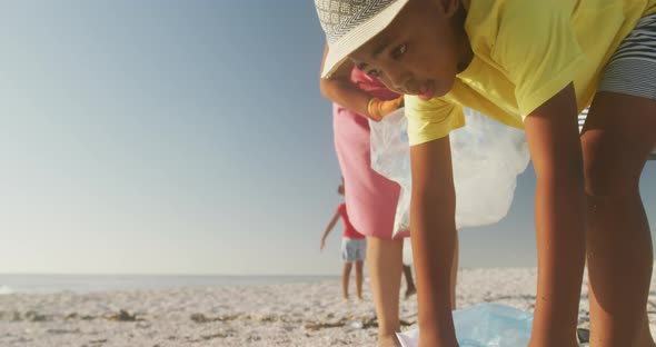 Senior african american couple with grandchildren segregating waste on sunny beach alt