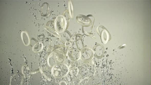 A Bunch of Onion Rings with Water Fly Up and Rotate in Flight alt