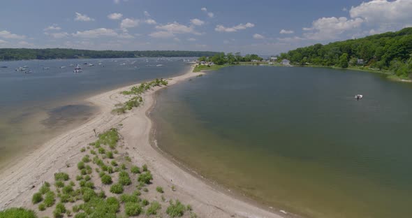 Flying Over a Thin Strip of Land and Towards Boats Anchored on Harbor alt