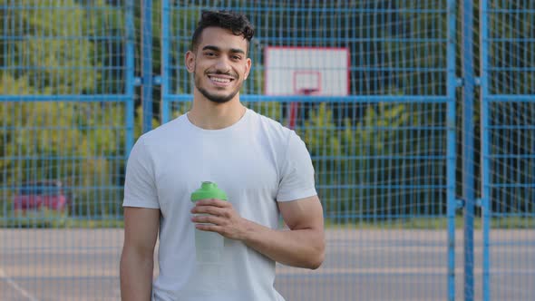 Happy Successful Middle Eastern Indian Man Athlete Latino Runner Holding Sports Bottle of Clean alt