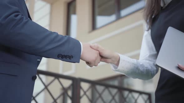 Two Young Unrecognized Man and Woman Business Partners Shaking Hands on the Terrace Close-up alt