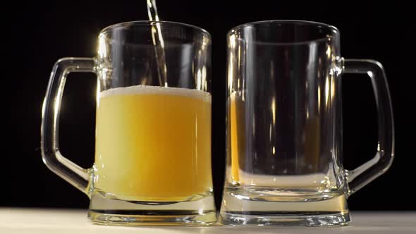 Two Beer Glasses Are Poured with Foamy Golden Light Beer on Black Background, Beer with Friend alt