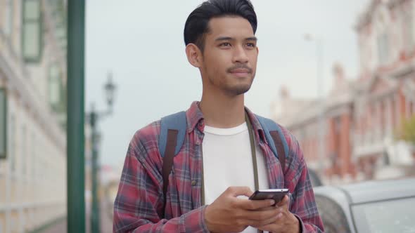 Tourists Asian man using a smartphone checking the map while standing beside the street.