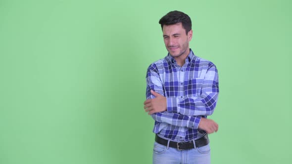 Stressed Young Hispanic Man Touching Something and Giving Thumbs Down alt