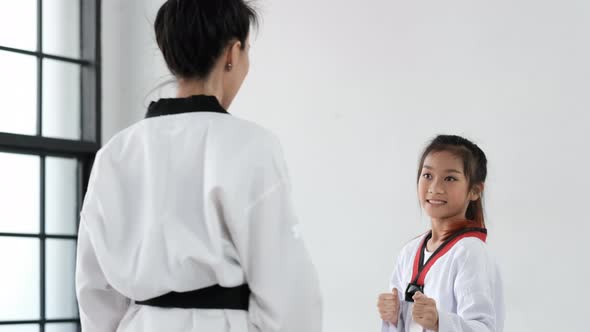 Taekwondo girl coach teach technique to her student for front kick in gym.