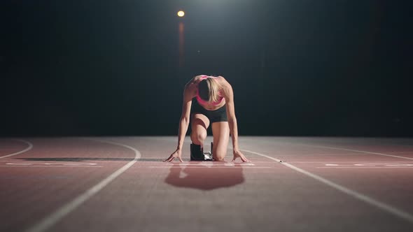 Front View of a Female Athlete Starting Her Sprint on a Running Track