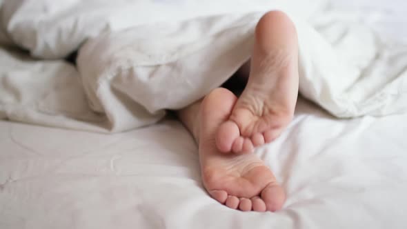 Woman legs under the covers in bed