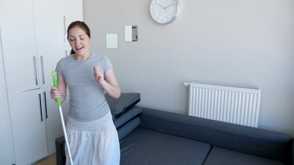 Happy Woman is Washing Floor Using Mop Singing a Song and Dancing in Her Modern Flat alt