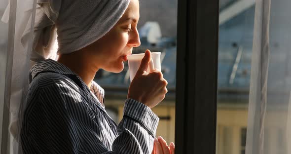 4 k. happy beautiful young woman with a towel on her head is having breakfast on the balcony, drink