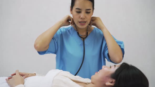 A doctor in hospital use stethoscope check the the lady patient laid on bed