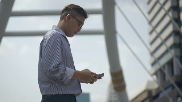 Portrait Asian businessman texting with a friend on smartphone at urban city.