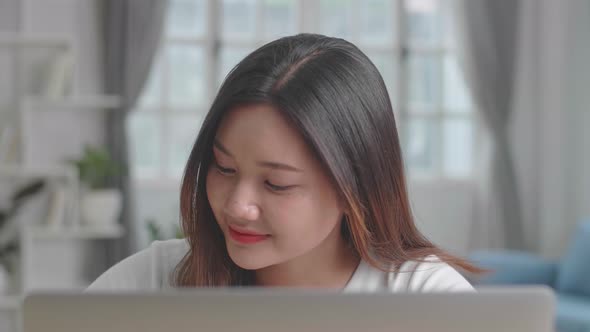 Asian Girl Using Laptop Computer And Writing On Notebook alt