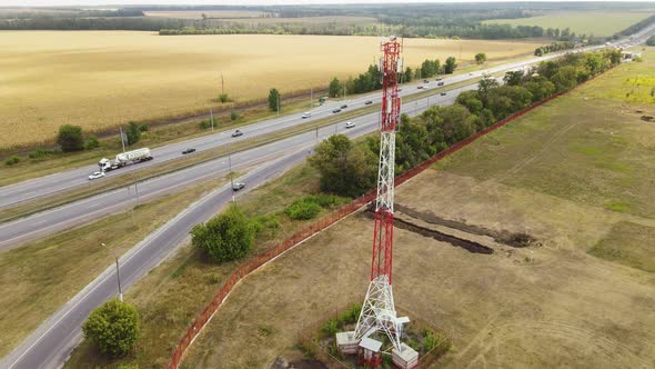Cell Site of Tower with 5G Base Station By Highway with Traffic Move Drive Cars alt