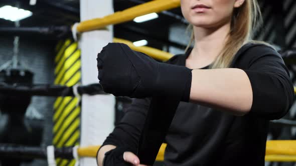 Female Boxer Ties Her Hands with a Black Bandage Before Training