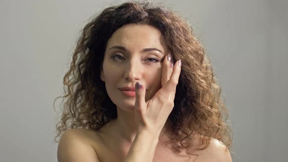 Beautiful Middleaged Woman Massages Her Face and Neck with Light Movements alt