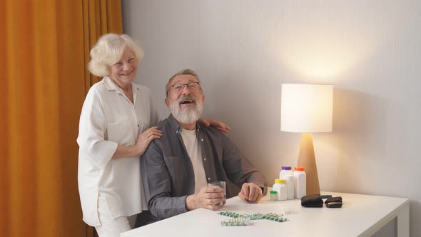 Senior Couple at Home Behind Table with Pills