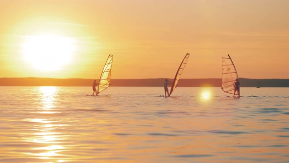 Sunset Lake with a Group of Man on Windsurf Boards alt