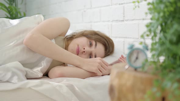 Beautiful Young Woman Opens Her Eyes and Wakes Up in Bed at Seven O'clock in the Morning alt