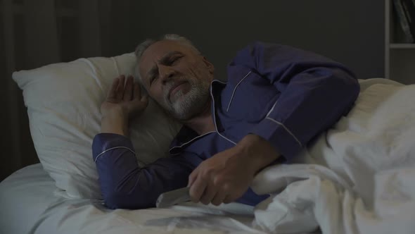 Annoyed Senior Man Suffering Insomnia and Nervously Switching Tv Channels alt