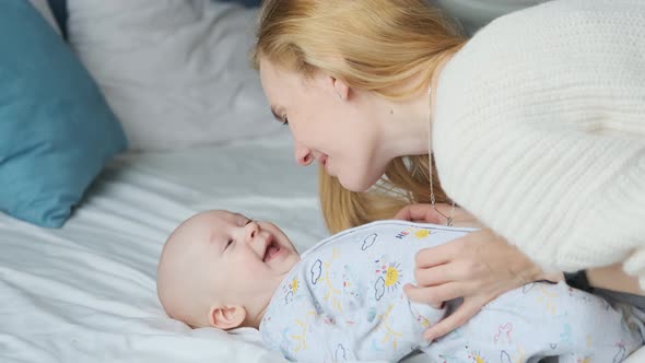 Caucasian woman basking with toddler in bed