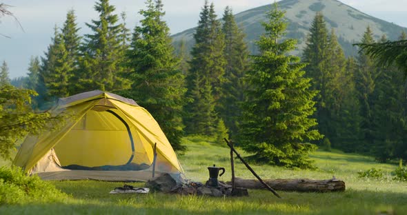 Tent and Bonfire on the Forest Lawn in the Mountains alt