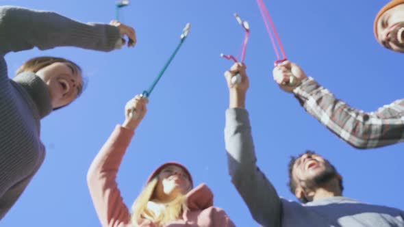 Group of friends standing above blu sky and doing victory gesture.