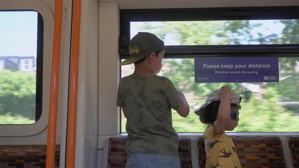 Kids on train ride playing and looking out the window during covid pandemic