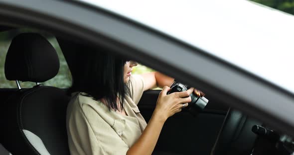 Woman photographer sitting in the car and looking on the photo on the camera alt