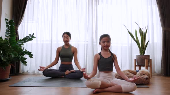 little girl oing practicing yoga with Healthy mom trainer together on yoga mat at home alt