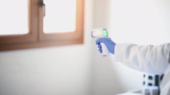 Doctor with Thermometer Measuring Temperature to Two Young Girls Wearing Mask alt