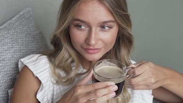 Blond Woman Relaxing On Sofa With Coffee